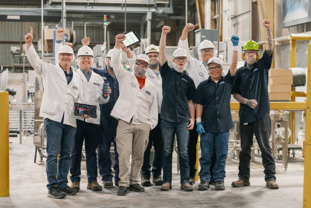 group of manufacturing workers raising their hands